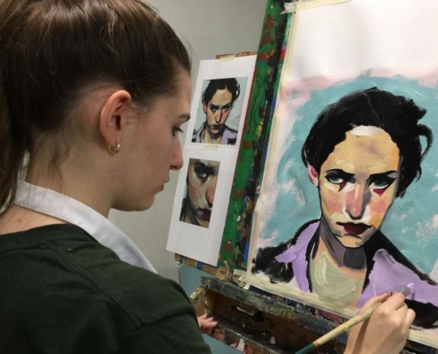 Student painting a portrait on canvas