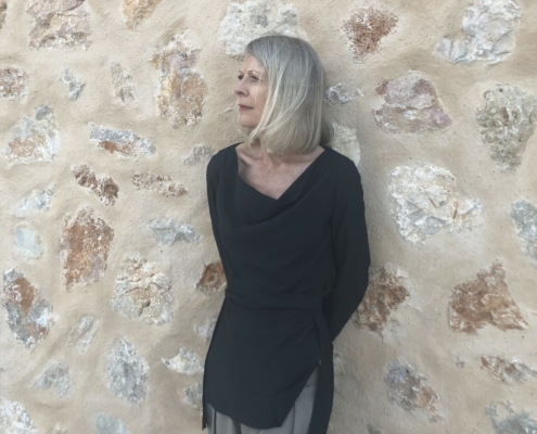 Lynn Cooke poses in front of a wall of rocks