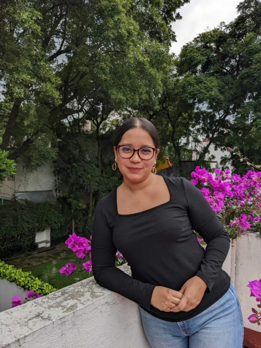 Sue Montoya Portrait by Berenicé Brino Sue Montoya in front of purple flowers