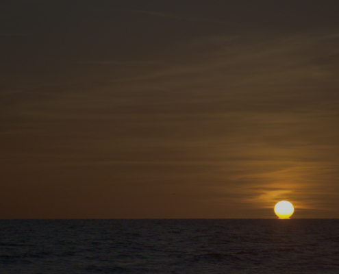 A setting sun touching the horizon line over the ocean