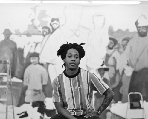 Reginald O' Neal on a stool in front of a in progress portrait mural