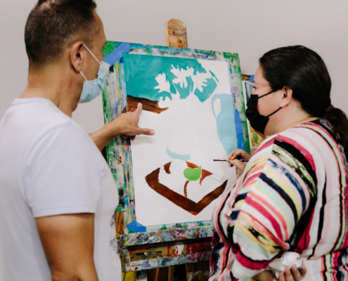 Two people in front of painting easel