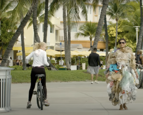 Woman on bike staring at woman covered in trash