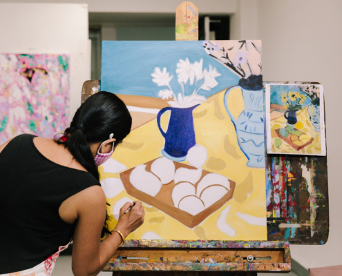 Young woman holds a brush painting on a canvas