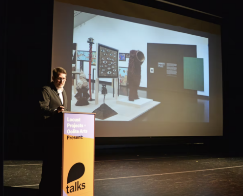 Ian Berry standing at a podium that says Talks with a projector to his left