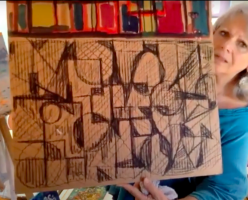 A lady with gray hair and blue blouse shows her drawing