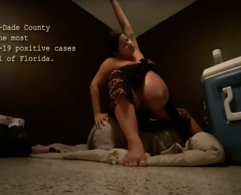 Pamela stretching on an exercise ball while pregnant. Her belly is bare and theres a cooler in front of her