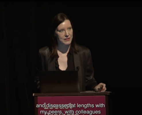 Rachel Kent lecturing against the Talks signage