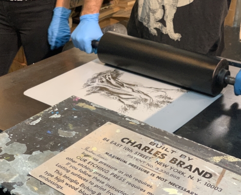 Hands start to push a roller over a print to make an impression
