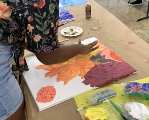 Student making her piece with clay on canvas